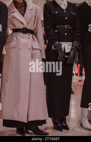 Détails à la mode d'un blazer classique noir et d'un long manteau beige avec ceinture chaude. Mode femme et accessoires élégants Banque D'Images