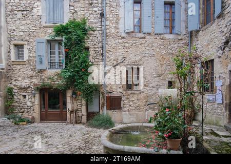 Maison ancienne en pierre fa¸çade avec volets bleus et fontaine dans le village médiéval de Chatillon en Diois dans le sud de la France (Drome) Banque D'Images