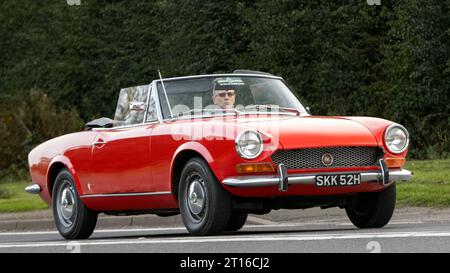 Bicester,Oxon.,UK - Oct 8th 2023 : 1969 rouge Fiat 124 voiture classique conduisant sur une route de campagne anglaise. Banque D'Images