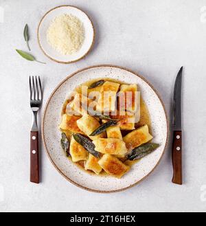 Gnocchi maison italien avec pommes de terre, fromage et beurre de sauge, servi dans une assiette sur une table lumineuse. Cuisine italienne. Pose à plat Banque D'Images