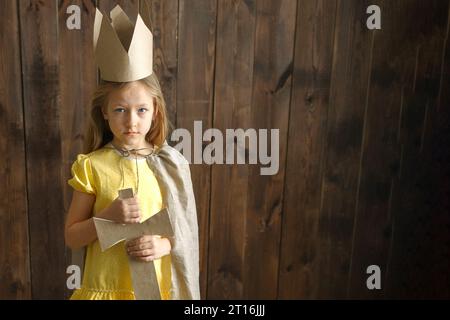 Portrait d'une jeune fille princesse avec une couronne en carton et une épée, à côté il y a un espace pour le texte. Bannière. Banque D'Images