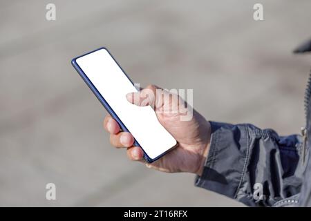 Détail de la main d'un homme latin tenant un téléphone portable avec un écran vide. Banque D'Images