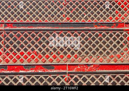 Marches d'escalier en métal avec peinture rouge écaillée. fond de texture métallique Banque D'Images