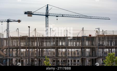 Bâtiment en construction avec grues et échafaudages dans la nouvelle zone d'expansion, Madrid, Espagne. Banque D'Images