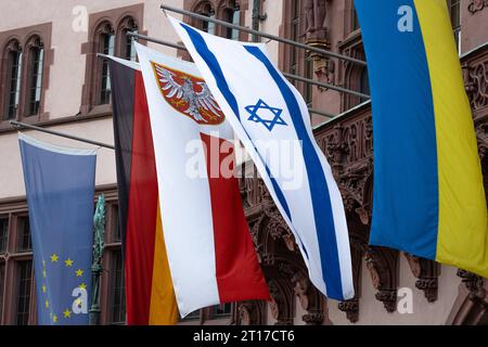 Solidarität mit Israel und der Ukraine am Balkon des Römers in Frankfurt am main sind zusätzlich zur Europa- und Deutschland-Fahne rechts sowie dem Frankfurter Stadtwappen Mitte aus Solidarität die Nationalflaggen Israels und der Ukraine rechts gehisst. AM 24. Februar 2022, begann die invasion russischer Truppen in die Ukraine. Seitdem dauert der Angriffskrieg Russlands an. AM 07. Oktober 2023 hatte die radikalislamische Hamas von Gaza aus überraschend einen Angriff auf Israel begonnen. Frankfurt am main Römerberg Hessen Deutschland *** solidarité avec Israël et l'Ukraine sur le balcon du Banque D'Images