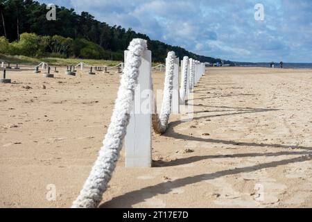 Une corde blanche épaisse en forme d'arc est suspendue sur des poteaux de bois dans le sable marin Banque D'Images