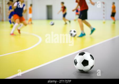 Cours d'entraînement de football en salle pour les enfants. Entraînement aux techniques de football. Joueurs de futsal dans le jeu d'entraînement à la salle de sport Banque D'Images