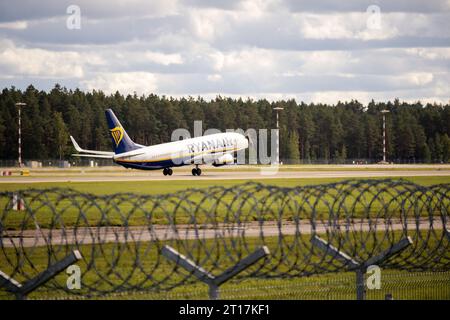 Un avion décolle de la piste de l'aérodrome avec un fond vert d'arbres à l'arrière et une clôture de fil barbelé au premier plan Banque D'Images
