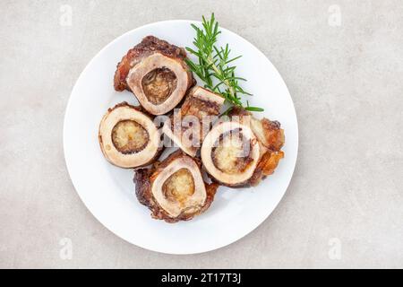 Os de moelle rôtis sur une assiette blanche avec garniture de romarin Banque D'Images