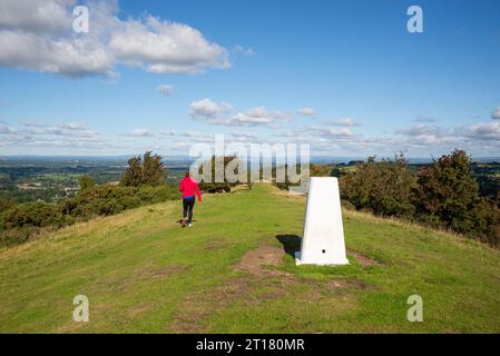 Une femme marchant devant le point trigger sur Kerridge Hill sur le sentier de Gritstone près de Bollington, Macclesfield, Cheshire, Angleterre. Banque D'Images