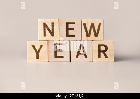 Le Word New Year sur des cubes en bois sur un fond studio neutre beige. Copier l'espace. Écrit. Les mots de texte comptent. Décorations de Noël. Inscription HAP Banque D'Images