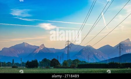 Les lignes de transport d'électricité à haute tension et les pylônes au lever du soleil s'étendent à travers la campagne vers les contreforts des Alpes françaises à Varces, Franc Banque D'Images