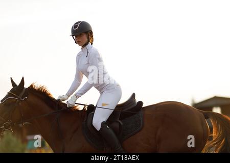 Femme cavalier jockey en casque et uniforme blanc préparant les courses de chevaux Banque D'Images