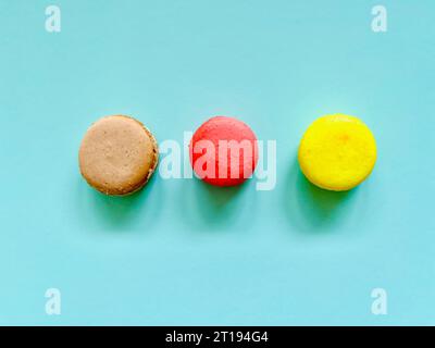 Vue aérienne de trois macarons assortis sur un fond turquoise Banque D'Images