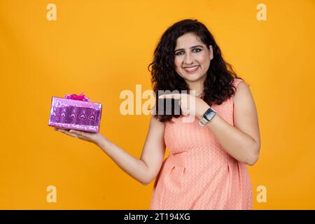 Femme indienne heureuse avec boîte cadeau sur fond isolé Banque D'Images