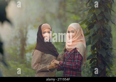 Deux femmes asiatiques souriantes portant un foulard se tenant la main Banque D'Images