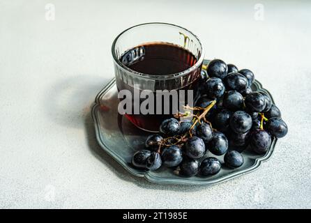 Verre de vin rouge avec une grappe de raisins noirs sur une assiette en étain Banque D'Images