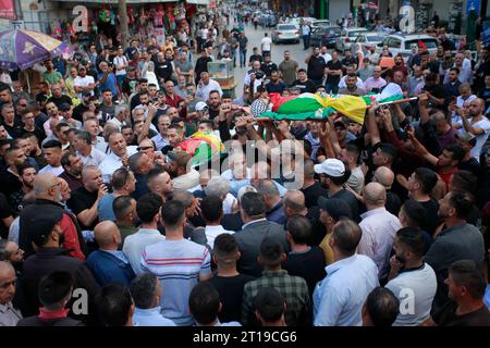 Des Palestiniens portent les corps d'Ibrahim Wadi, 62 ans, et son fils Ahmad Wadi, 25 ans, des Palestiniens portent les corps d'Ibrahim Wadi, 62 ans, et son fils Ahmad Wadi, 25 ans, deux des quatre Palestiniens tués par des colons juifs la veille, lors de leurs funérailles dans la ville de Naplouse en Cisjordanie le 12 octobre 2023. Au moins quatre Palestiniens ont été tués le 11 octobre 2023, alors que des colons israéliens armés attaquaient une ville au sud de Naplouse, en Cisjordanie occupée, a déclaré le ministère palestinien de la Santé. Photo de Mohammed Nasser apaimages Naplouse Cisjordanie territoire palestinien 12102 Banque D'Images