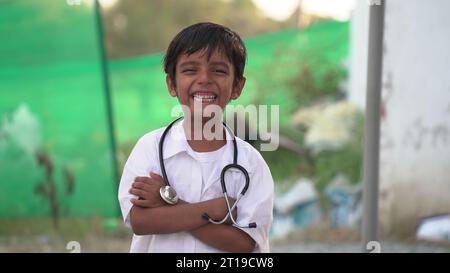 Mignon petit garçon indien porter un uniforme médical tenant stéthoscope jouant le médecin, heureux drôle petit enfant d'âge préscolaire de race mixte prétendant pediatrici Banque D'Images