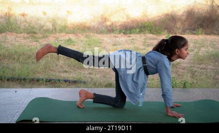 Portrait de magnifique enfant pratiquant le yoga en plein air. Bel enfant pratique le yoga asana ou fait des exercices de gymnastique. Petits enfants méditant dans lotus po Banque D'Images