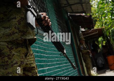 El Salvador, El Salvador. 11 octobre 2023. Un soldat lourdement armé monte la garde dans le quartier de Valle Verde. Dans la lutte controversée contre la criminalité menée par le président conservateur Bukele, l'armée joue un rôle important dans ce pays d'Amérique centrale. Depuis un an et demi, le pays est en état d ' urgence avec restrictions des droits fondamentaux. Crédit : Camilo Freedman/dpa/Alamy Live News Banque D'Images