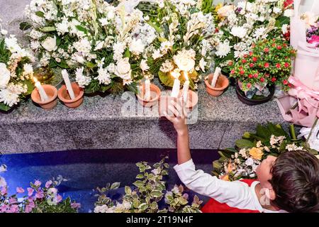 Badung, Indonésie. 12 octobre 2023. Un enfant allume une bougie comme veillée pour les victimes au mémorial du gorund zéro. Bali pour commémorer le 21e anniversaire de l'explosion consécutive connue sous le nom d'attentat de Bali, qui a tué 202 personnes de différentes nationalités dans la région de Legian. Crédit : SOPA Images Limited/Alamy Live News Banque D'Images