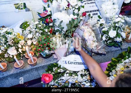 Badung, Indonésie. 12 octobre 2023. Une femme met des fleurs dans une veillée pour les victimes au mémorial du gorund zéro. Bali pour commémorer le 21e anniversaire de l'explosion consécutive connue sous le nom d'attentat de Bali, qui a tué 202 personnes de différentes nationalités dans la région de Legian. Crédit : SOPA Images Limited/Alamy Live News Banque D'Images