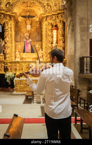 Personne jouant du violon. Violoniste caucasien portant des vêtements classiques et se produisant dans un espace clos, église. Spectacle en direct. Image verticale Banque D'Images