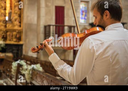 Personne jouant du violon. Violoniste caucasien portant des vêtements classiques et se produisant dans un espace clos, église. Spectacle en direct. Image horizontale Banque D'Images