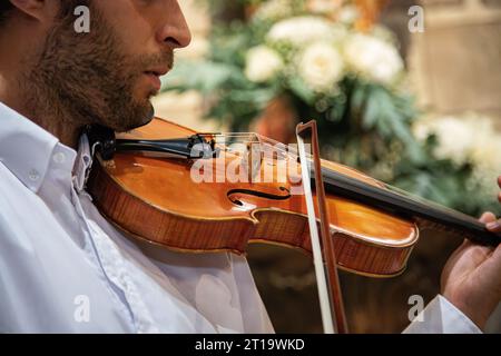 Personne jouant du violon. Violoniste caucasien portant des vêtements classiques et se produisant dans un espace clos, église. Spectacle en direct. Image horizontale Banque D'Images