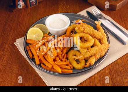 Fruits de mer frits servis avec frites de patates douces et sauce Banque D'Images