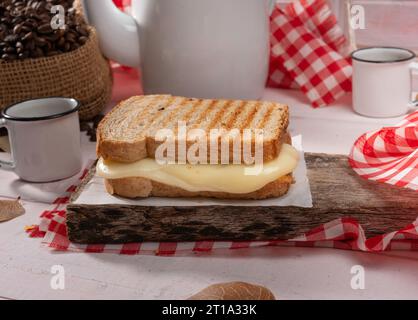 sandwich au pain avec fromage sur un ensemble rustique fin avec table en bois blanc, grains de café et tissu rouge Banque D'Images