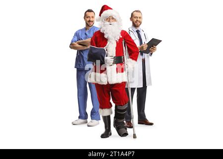 Père noël avec une attelle de pied et harnais de bras debout avec une équipe médicale isolée sur fond blanc Banque D'Images