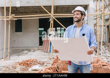 Travaux de constructeur d'ingénieur de construction sur le chantier de construction. Architecte chef de projet de maison chef concepteur heureux avec le plan d'étage. Banque D'Images