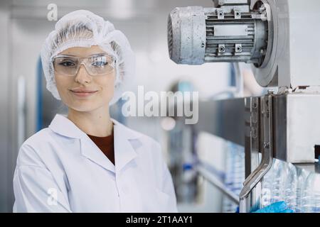 Portrait femmes heureuses travaillant dans une usine d'hygiène dans la production de bouteilles en plastique PET d'eau potable en ligne propre Banque D'Images