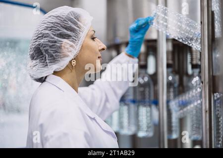 Les travailleuses travaillant dans l'usine d'hygiène dans la production de bouteilles en plastique PET d'eau potable de ligne propre Banque D'Images