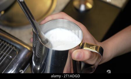 Le barista fait cuire le lait à la vapeur. Le processus de création de mousse de lait. Procédé de fabrication de lattes. boisson au café latte gros plan barista fouet le lait dans un pichet avec Banque D'Images