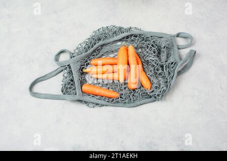 Carottes fraîches dans un sac d'épicerie en maille réutilisable, légumes du marché, aliments sains et zéro déchet Banque D'Images