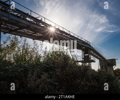 Sunburst à travers un convoyeur désaffecté au-dessus du chemin piétonnier Banque D'Images