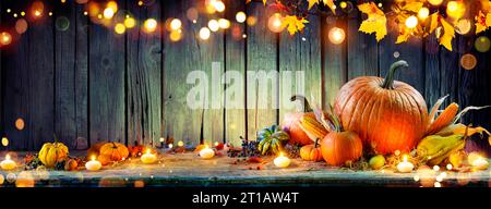 Thanksgiving - citrouilles et épis de maïs sur une table rustique avec guirlande et lumières abstraites défocalisées Banque D'Images