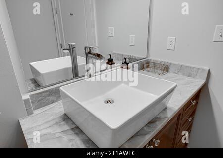 Intérieur de la salle de bains moderne de l'appartement avec lavabo de luxe et comptoirs en pierre de marbre et meuble-lavabo en bois avec miroir Banque D'Images