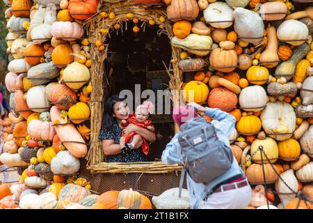 Dallas, États-Unis. 12 octobre 2023. Une femme tenant un bébé pose pour une photo au Dallas Arboretum's Pumpkin Village, Texas, États-Unis, le 12 octobre 2023. Le célèbre village de citrouilles de Dallas arboretum présente des maisons de citrouilles et des expositions créatives conçues à partir de plus de 100 000 citrouilles, gourdes et courges. Crédit : Dan Tian/Xinhua/Alamy Live News Banque D'Images