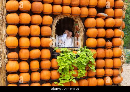 Dallas, États-Unis. 12 octobre 2023. Une femme tenant un bébé est vue à l'intérieur d'une maison de citrouilles dans le village de citrouilles de Dallas Arboretum, Texas, États-Unis, le 12 octobre 2023. Le célèbre village de citrouilles de Dallas arboretum présente des maisons de citrouilles et des expositions créatives conçues à partir de plus de 100 000 citrouilles, gourdes et courges. Crédit : Dan Tian/Xinhua/Alamy Live News Banque D'Images