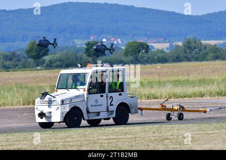 Flugzeugschlepper beim Tag der Bundeswehr Ein kleiner Flugzeugschlepper fährt über die Landebahn des Militärflugplatzes in Bückeburg. Im hintergrund sind Schulungshubschrauber EC 135 zu sehen. Spotterday zum Tag der Bundeswehr TdBW in Bückeburg 2023 an diesem Tag wurden interessierte Fotografen zum sogenannten Spotterday eingeladen. Dieser fand in Vorbereitung zum jährlich ausgerichteten Tag der Bundeswehr am Internationalen Hubschrauber Ausbildungszentrum statt. Bückeburg Niedersachsen Allemagne *** tracteur d'avion à la Journée des forces armées allemandes Un petit tracteur d'avion roule au-dessus du Banque D'Images