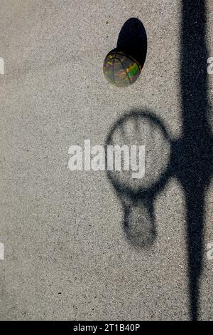 Ombre d'un basket-ball Hoop et une vraie basket ball contre le sol avec la lumière du soleil en Suisse Banque D'Images