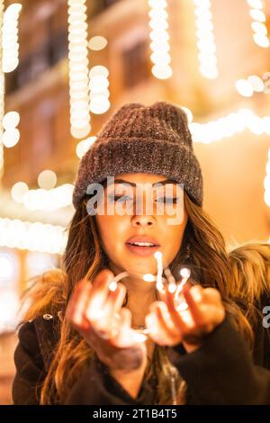Shooting de Noël avec des lumières de Noël, caucasien dans la ville la nuit à côté des lumières de Noël. Élégante robe noire de noël ou du nouvel an Banque D'Images