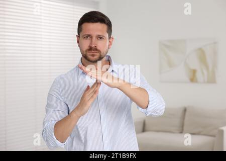 Bel homme montrant le geste de temps à la maison, espace pour le texte. Signal d'arrêt Banque D'Images
