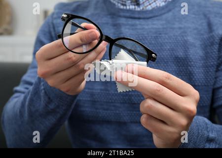 Homme essuyant les lunettes avec un chiffon en microfibre à l'intérieur, gros plan Banque D'Images