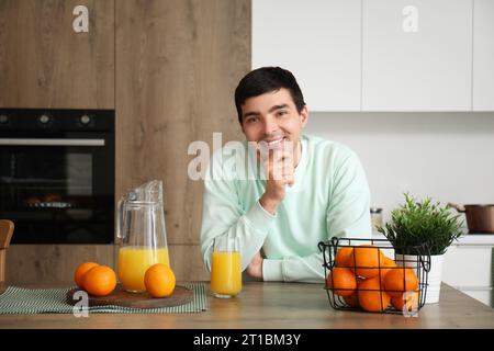 Jeune homme avec des oranges et du jus dans la cuisine Banque D'Images