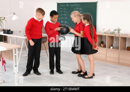 Petits camarades de classe avec globe en classe Banque D'Images